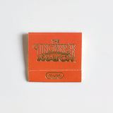 An orange "Matches | The Incense Match" booklet from The Incense Match brand, labeled "musk," sits on a white background—ideal as an incense gift or air freshener with convenient incense matches.