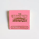 A pink booklet labeled "Matches | The Incense Match" by The Incense Match, with "oriental blossom" at the bottom, features incense matches that act as air fresheners, displayed on a plain white background.