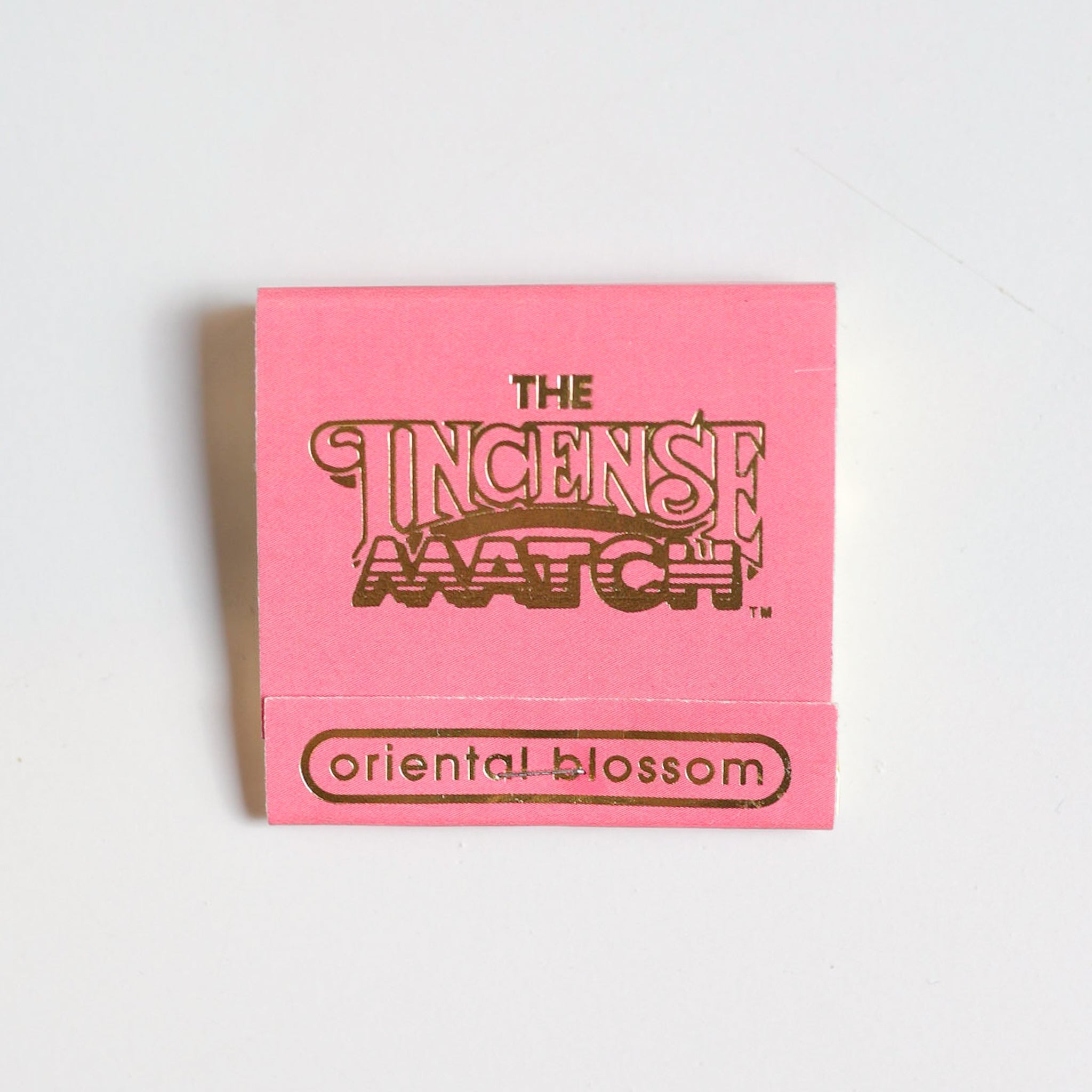 A pink packet labeled "Matches | The Incense Match" by The Incense Match, with "oriental blossom" at the bottom, offers incense matches for instant air freshening, shown against a plain white background.