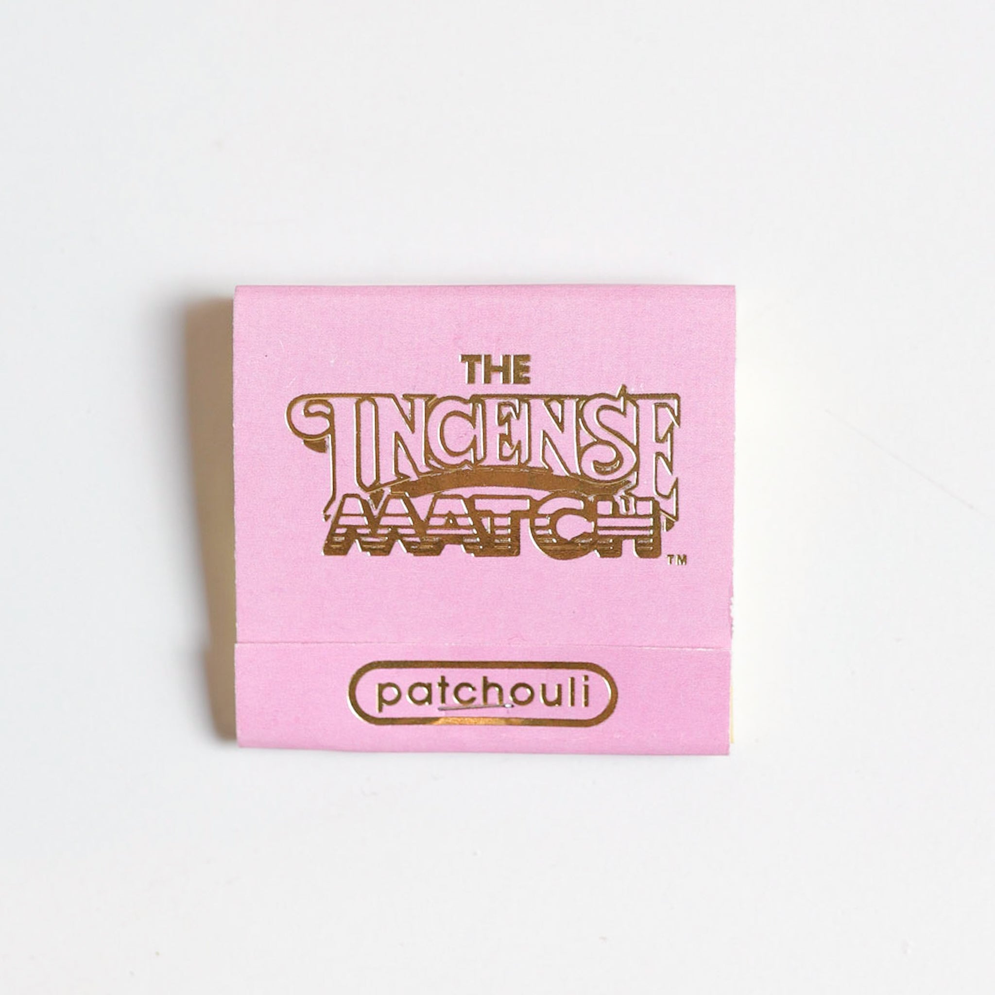 A pink "The Incense Match" matchbook in patchouli scent by The Incense Match—ideal as a unique air freshener or incense gift—shown on a white background.