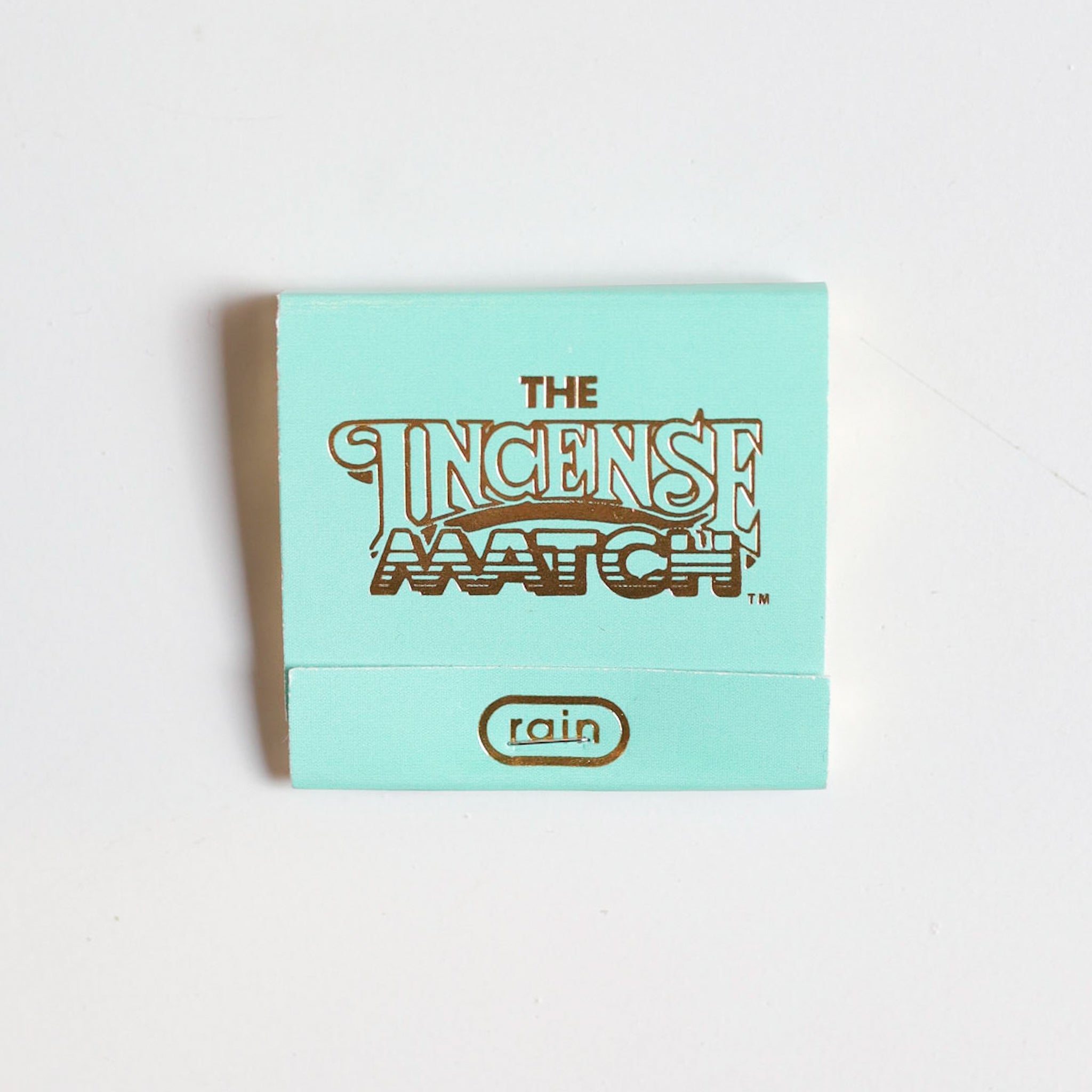 A light blue booklet of "Matches | The Incense Match" by The Incense Match, featuring the rain scent on the cover, serves as both incense and air freshener, shown against a white background.