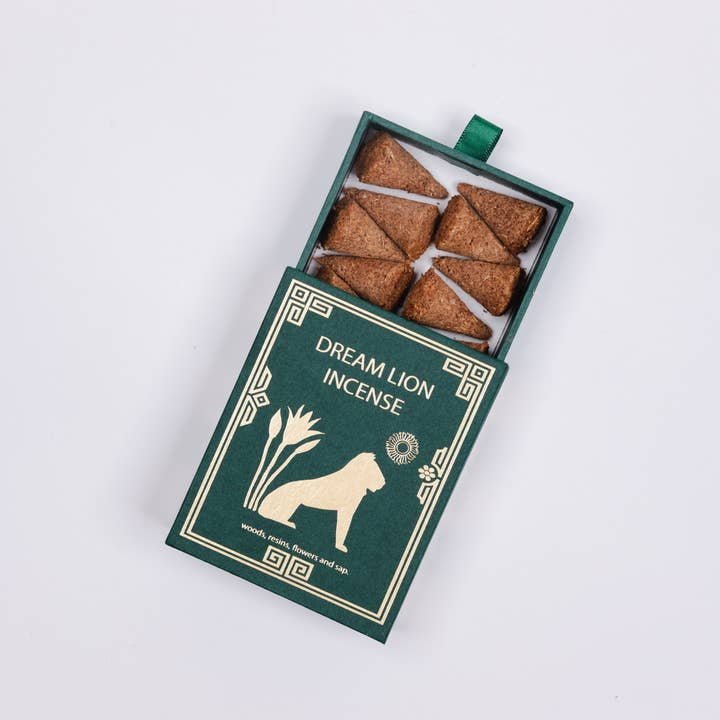 A green box labeled "Mayan Copal + Desert Sage Incense | Dream Lion" is partially open, revealing six brown, triangular cones inside—ideal for purification rituals with the calming scent of desert sage. Brand: Dream Lion Incense.