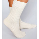 A person wearing Mere Cashmere Ankle Socks by Tailored Union stands on a light-colored surface.