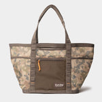 The Duck Camp Mesh Gear Tote features a camo mesh build, dual handles, front zip pocket with orange pull, and a lower front logo—ideal for carrying outdoor gear on your next adventure.
