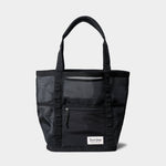 The Duck Camp Mesh Gear Tote features black mesh, dual handles, a front zippered pocket, and a white Drake Camp label—ideal for storing outdoor essentials or everyday gear.