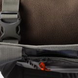 Close-up of a gray strap and buckle on the Duck Camp Mesh Gear Tote, showing its brown fleece lining and a partially open pocket with an orange zipper pull.