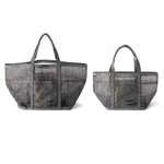 Two gray Mesh Gear Totes by Duck Camp, with handles, front pockets, camouflage pattern, and orange zippers, are shown side by side in different sizes.