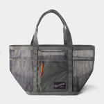 The Duck Camp Mesh Gear Tote is a gray camouflage heavy-duty bag featuring breathable mesh side panels, dual handles, a front zip pocket with orange pull, and a "Park Clamp" logo on the front.