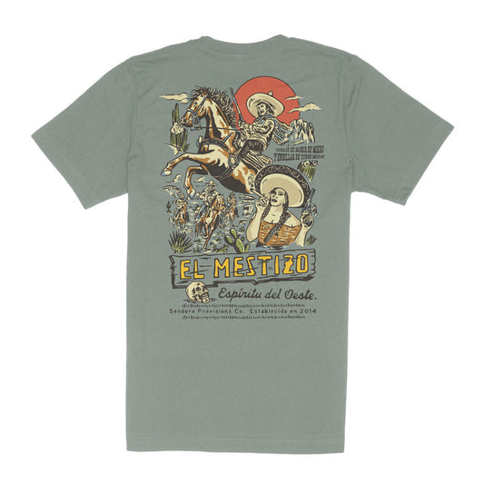 The Mestizo tee by Sendero Provisions Co. is sage green with a vibrant back graphic featuring a Wild West cowboy on horseback, cacti, a guitarist woman, and the text "El Mestizo - Espíritu del Oeste.