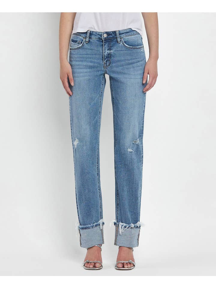 A person wears Vervet's Mid Rise Cuffed Straight Jean in light blue with distressed hems and minor rips, styled with a white top and open-toe heels against a plain background.