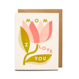The Mom I Love You Card by Worthwhile Paper features a pink flower with "Mom I Love You" on its petals and leaves, plus an envelope behind the card—a perfect Mother’s Day greeting from the Worthwhile Cards collection.