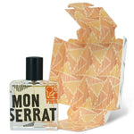A square glass perfume bottle labeled "Monserrat" from Fzotic, with a black cap, is displayed next to an orange and white patterned box, suggesting a fresh Mediterranean scent.