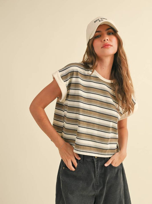 A woman in a Miou Muse Multi Stripe T-Shirt, black pants, and a beige baseball cap stands against a plain light background with one hand in her pocket.
