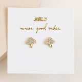 The Mushroom Pave Stud Earring by JaxKelly features gold and crystal mushroom-shaped, hypoallergenic studs, shown on a white "JaxKelly" card with the phrase "wear good vibes.