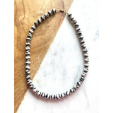 The Nara Beaded Necklace by Jessica Matrasko Jewelry features alternating black and white round beads with gold filled findings, displayed on wood and white marble for an elegant, timeless look.