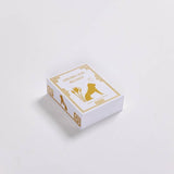 A white rectangular box labeled "Dream Lion Incense - Nine Treasures" with gold line art of a seated figure and floral accents on the lid, featuring calming pinyon pine incense, sits on a plain white background.