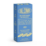 Blue and yellow box of Blomb No.03 Eau de Parfum, featuring Mediterranean fig, heliotrope, and vanilla notes, with text emphasizing the fragrance’s unique and inclusive character.