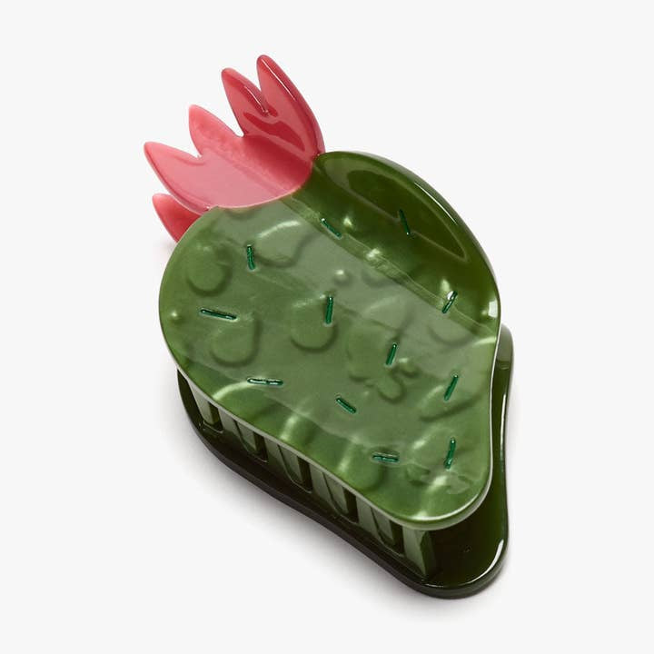 The Nopal Succulent Cactus Hair Claw Clip by Winona Irene is a green and pink plastic hair accessory shaped like a cactus, featuring short bristles on the flat surface for scalp massage.
