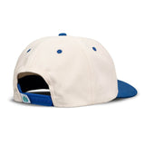 The Not Catching Hat by Sendero Provisions Co. is a white and blue embroidered twill baseball cap with a blue snap closure and a small green leaf design above the back closure.