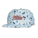 The Oasis Hat by Sendero Provisions Co. is a light blue 5-panel cap with cactus, sun, bottle, and cooler graphics, plus a pink and yellow embroidered felt logo on the front.