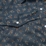 Close-up of the Howler Brothers Open Country Tech Shirt in Rancher Floral, featuring a dark blue small floral pattern, pearl snap buttons, a pointed flap pocket, and UPF 35 sun protection.