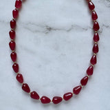 The Ophelia Necklace by Jessica Matrasko Jewelry features red jade teardrop beads separated by small gold-filled spacers, shown on a white marble surface.