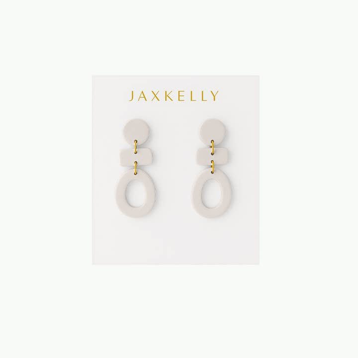 The Organic Three Tier Clay Earring in Oat Milk by JaxKelly features geometric, off-white polymer clay tiers with gold connectors—stylish, lightweight earrings on a branded card, ideal for everyday wear.