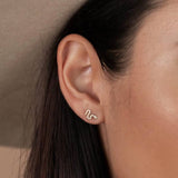 Close-up of a woman's ear with the Pave Stud Snake Gold Earrings by JaxKelly, tarnish-free; part of her face and dark hair are visible.