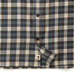 The Duck Head Performance Flannel Sport Shirt features a blue, beige, and black plaid pattern with black buttons and a partially unbuttoned bottom revealing a small logo tag.