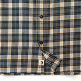 Close-up of the Duck Head Performance Flannel Sport Shirt in blue, beige, and white with black buttons and a small face icon tag near the hem.