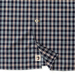 Close-up of the Duck Head Performance Poplin Sport Shirt, a navy, brown, and white plaid button-down with button placket and a small logo tag near the bottom hem.