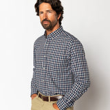Man with dark hair and beard wearing the Duck Head Performance Poplin Sport Shirt in blue, white, and red plaid with beige pants, standing against a plain white background.