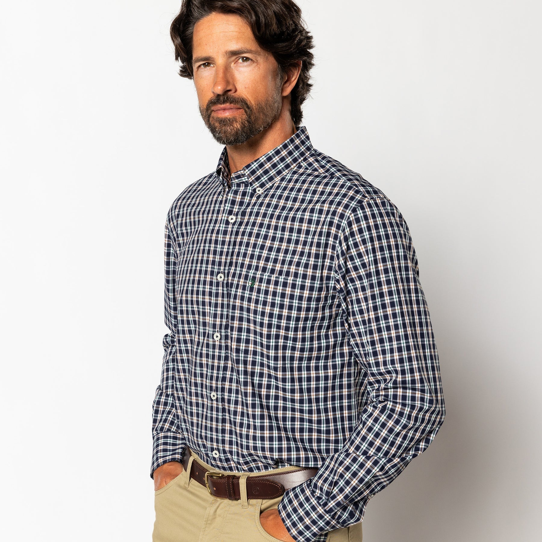 Man with dark hair and beard wearing the Duck Head Performance Poplin Sport Shirt in blue, white, and red plaid with beige pants, standing against a plain white background.
