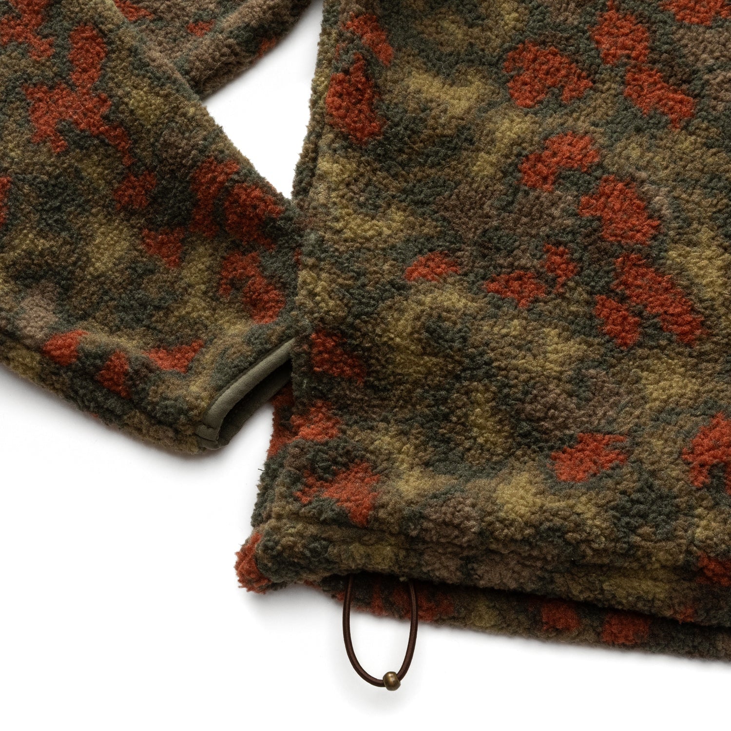 Close-up of the Duck Head Pineview Fleece 1/4 Snap Pullover featuring a green and orange camo print, drawstring hem, and sleeve detail—ideal for hiking—shown against a white background.