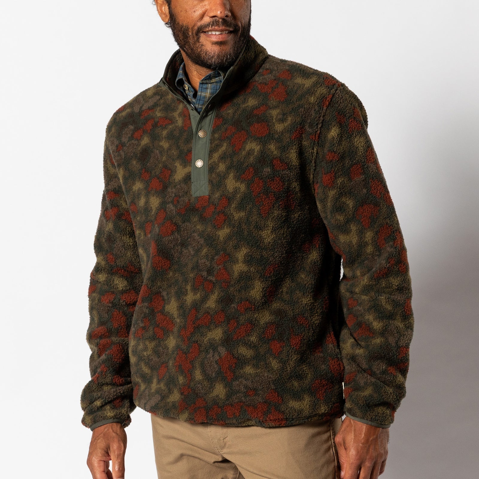A man wears the Duck Head Pineview Fleece 1/4 Snap Pullover over a plaid shirt with khaki pants, standing against a plain background.