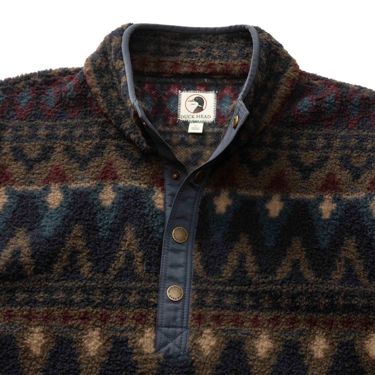 The Pineview Fleece 1/4 Snap Pullover by Duck Head features a patterned design, snap-button collar, and brand label on the inside neck—ideal for hiking or camping adventures.