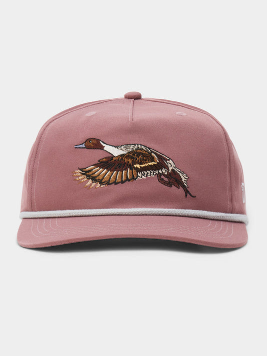 The Pintail Hat by Duck Camp is pink with white trim and features an embroidered flying duck (bull sprig) on the front.