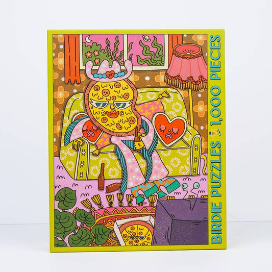 Pizza For One by Birdie Puzzles is a vibrant 1,000-piece puzzle featuring a cartoon bird-faced character on a patterned couch in a whimsical living room—crafted from recycled materials.