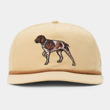 The Pointer Hat by Duck Camp is a beige adjustable cap with an embroidered brown and white dog on the front, made from a comfortable polyester shell.