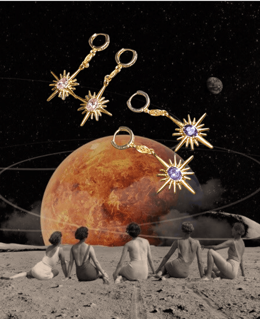Four women sit on a moon-like surface gazing at a planet; Minh Atelier’s Polaris Earrings, plated in 18k gold and adorned with gemstones and Swarovski crystals, float above them against a dreamy space backdrop.