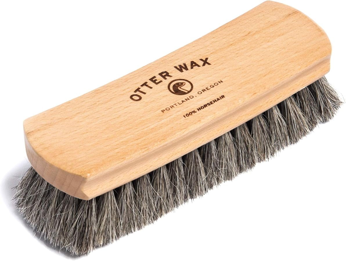 The Otter Wax Premium Horsehair Shoe Brush features a wooden handle and gray bristles, labeled "Otter Wax Portland, Oregon 100% Horsehair.