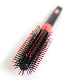 The Uppercut Deluxe Quiff Roller is a black, round hair styling brush with red-tipped bristles, perfect for creating a pompadour, shown on a white background.