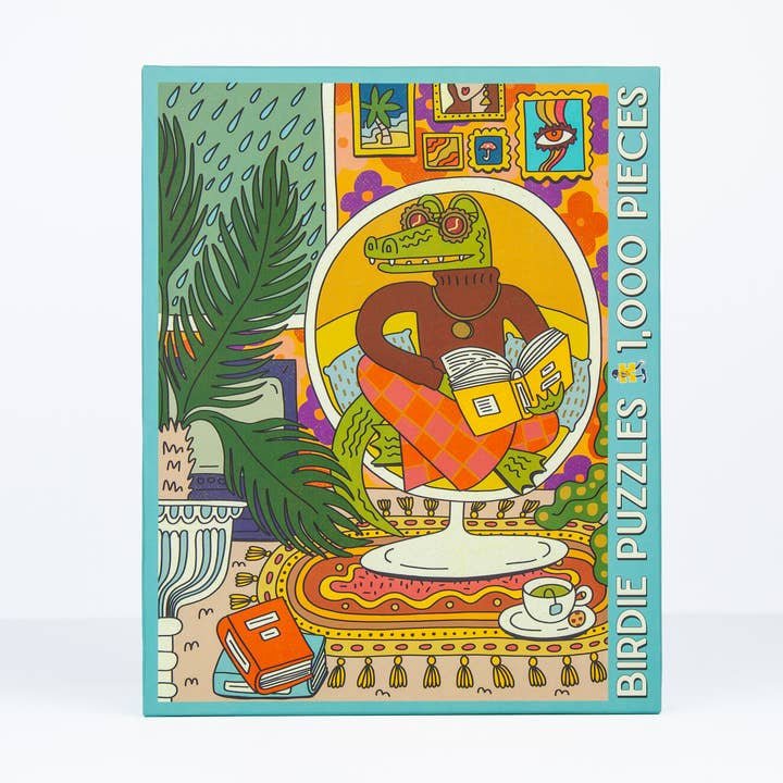Rainy Day 1,000 Pieces by Birdie Puzzles is an eco-friendly puzzle featuring an illustrated alligator in a sweater reading a book in a vibrant room, crafted from recycled materials.