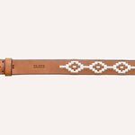The Rambler by Zilker Belts is a light brown Argentine leather belt with a brass buckle, white geometric bead pattern, and "ZULKER" embossed near the buckle—distinctively hand-stitched.