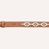 The Rambler by Zilker Belts is a light brown Argentine leather belt with a brass buckle, white geometric bead pattern, and "ZULKER" embossed near the buckle—distinctively hand-stitched.
