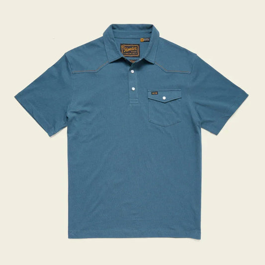 The Howler Brothers Ranchero Polo in Stargazer is a blue short-sleeve 100% cotton shirt with a collar, three-button placket, chest pocket with buttoned flap, and classic western yokes for style.