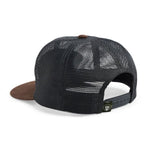 The Redfish Feedstore Snapback by Howler Brothers is a black mesh unstructured hat with a pliable brim, brown details, an adjustable snapback closure, and a small logo tag visible on the back.