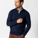 Man wearing the Duck Head Ridley 1/4 Zip Sweater in navy over a collared shirt and brown pants, standing against a plain white background.