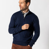 A man in a Duck Head Ridley 1/4 Zip Sweater over a collared shirt and brown pants stands against a plain white background, looking left.