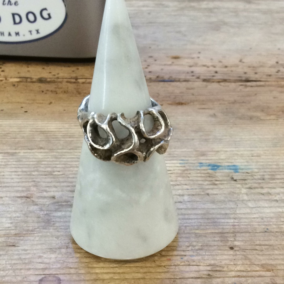 The Bird of Prey Ring | Silver Leaf showcases a bold, organic openwork design in sculptural silver, elegantly displayed on a white marble holder atop a wooden surface.